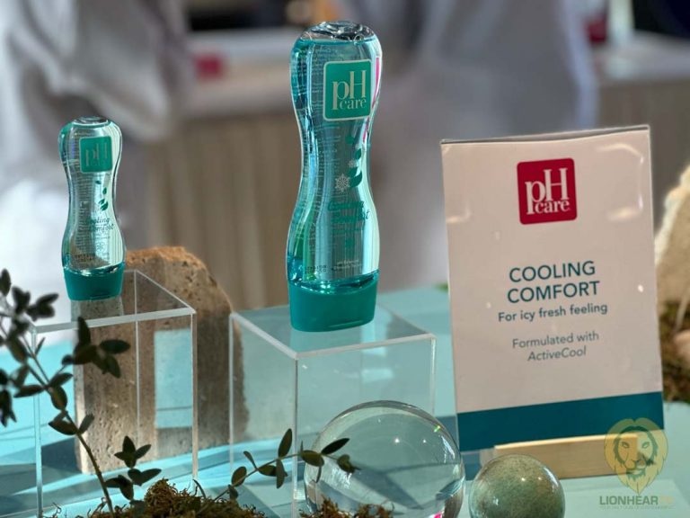 Display of pH Care feminine wash bottles with a sign highlighting 'Cooling Comfort' benefits, set on a turquoise-themed table with decorative plants and stones